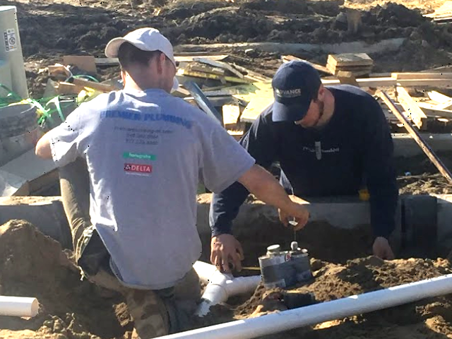 two plumbers setting up piping for new construction site