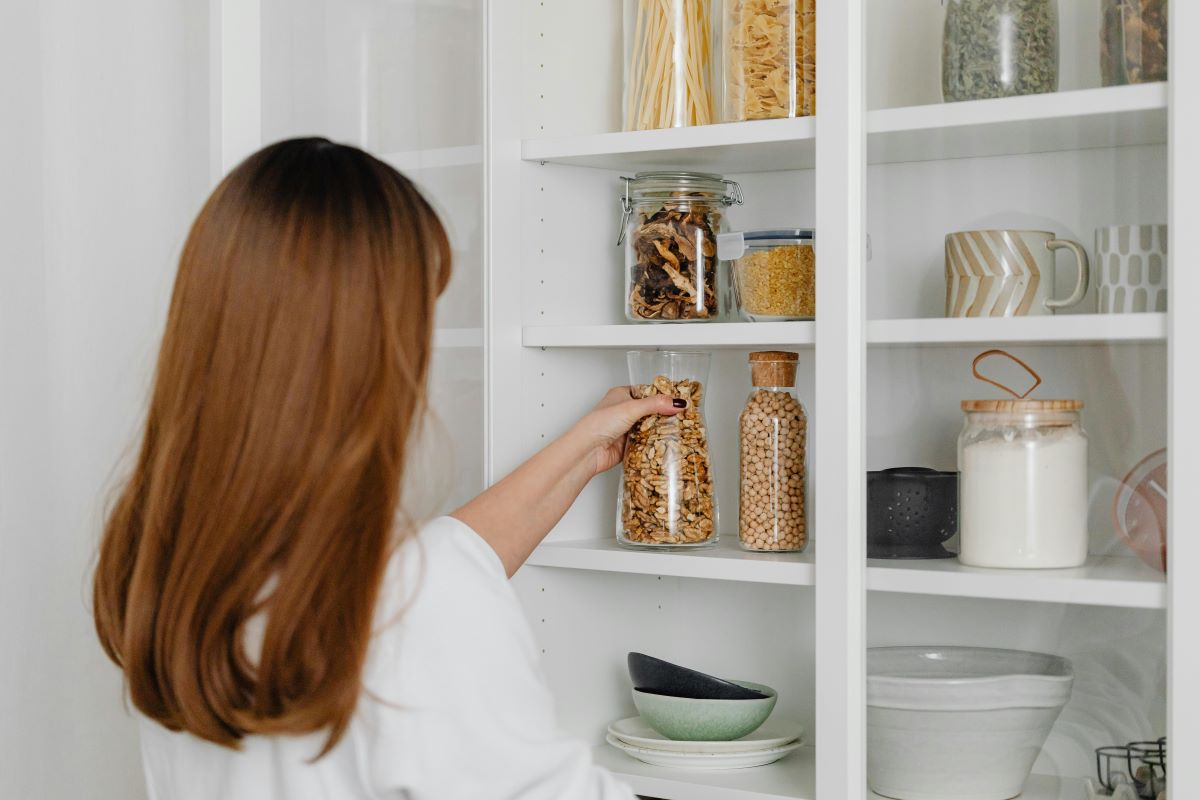 Woman in kitchen holding clear glass jar